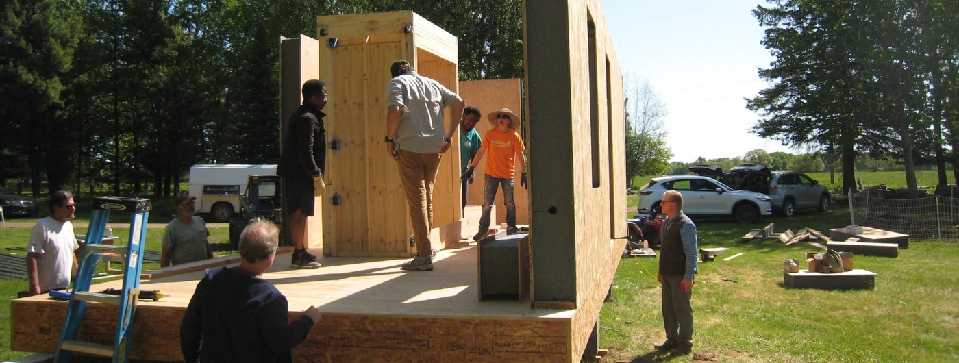 Group of adults working on building a house on a large trailer.