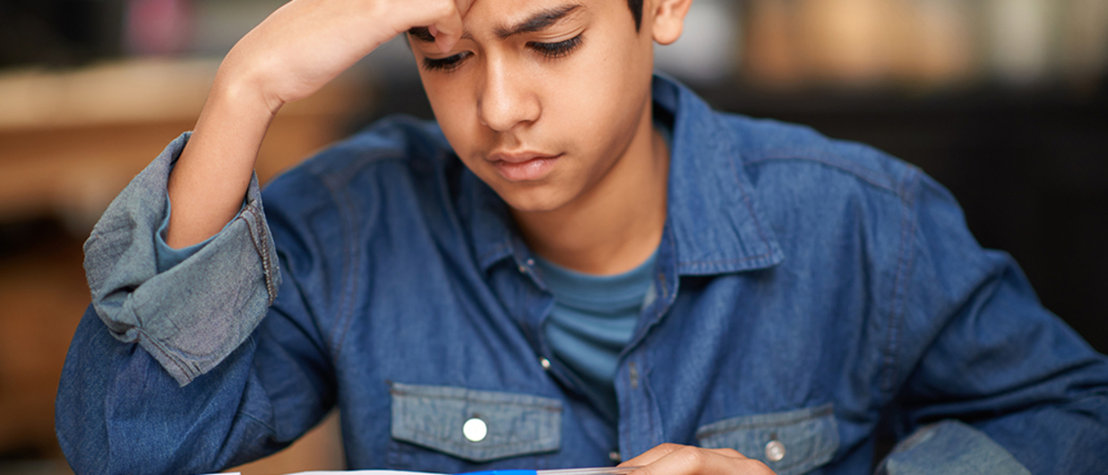 Young boy holding his hand to his head as he's studying.