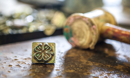 A stamp of the 4-H clover emblem next to a wooden gavel. 