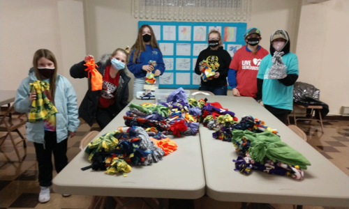 4-H kids holding up winter gear they made.