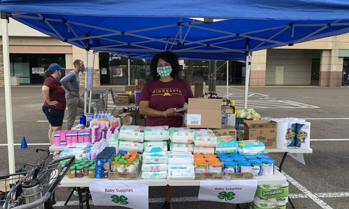 woman standing at a essential supply drive table