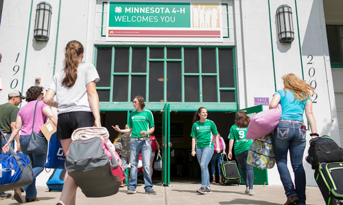People entering the 4-H building at the State Fair with 4-H ambassadors greeting them.