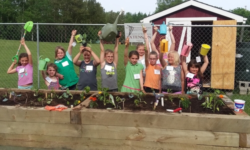 kids holding up gardening tools
