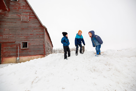 Boys playing near barn in winter