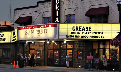 A movie theater at dusk with "Grease" on the display board.