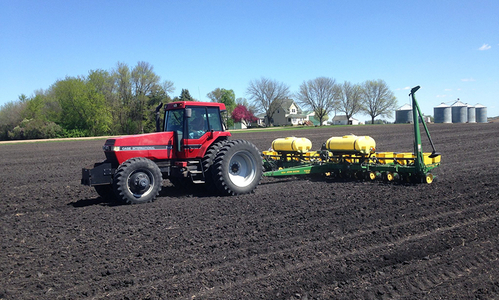 Tractor fertilizing a freshly plowed field. 