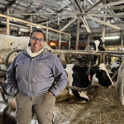 Dana stands in front of three dairy cows smiling