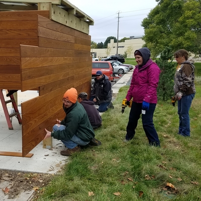 Volunteers help to build a wooden bike shed