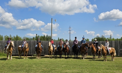 A line of 4-H youth members on horses outside. 