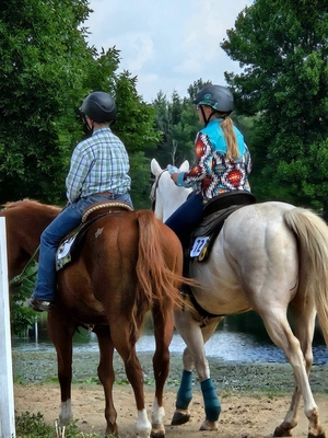 Two youth riding horses side by side