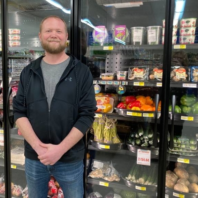 Aaron Bakke standing in front of grocery store refrigerators.