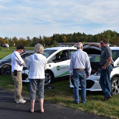 Adults looking and three different electric vehicles.