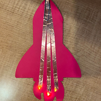 A red paper rocket with copper tape on it and lights at the end.