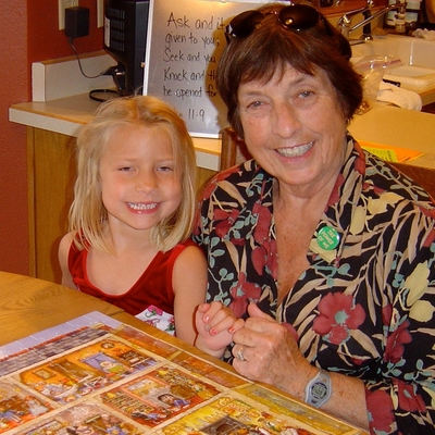 Grandmother and grand daughter complete a puzzle at kitchen table
