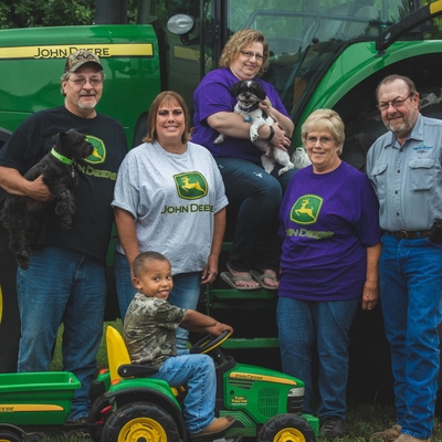 Ackerman family standing together in front of a John Deere tractor.
