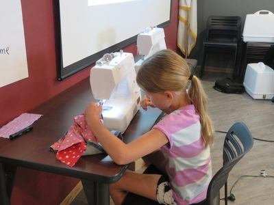 4-H youth working on project with sewing machine at 4-H camp