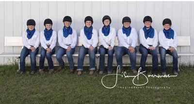 Row of drill team riders dressed in white shirts with blue scarves.