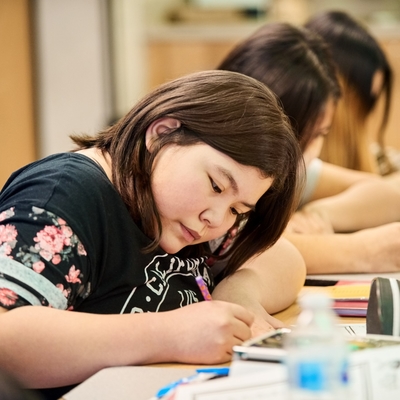 Students work on paper in a classroom together