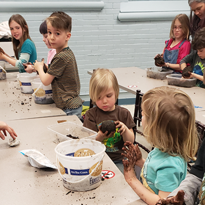 Kids at a table playing with buckets of dirt.