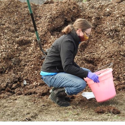 Person filling a bucket with compost.