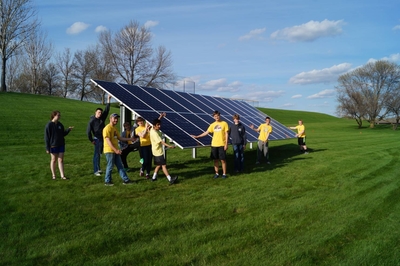 Group of people around a ground mounted solar panel.