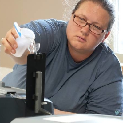 Person pouring water into a testing machine.