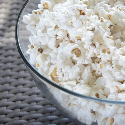 A close up of a glass bowl holding popcorn.