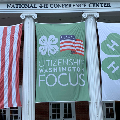 American flag, 4-H clover flag, and a green flag that says "Citizenship Washington Focus" hang at the entrance of the National 4-H Conference Center