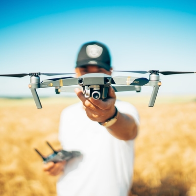 A person holding a drone in a field.