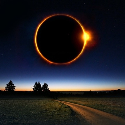 A giant solar eclipse in the sky with a road in the foreground and trees on the horizon.