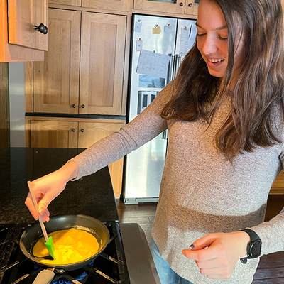 Teen girl smiles while tending omelet on stove
