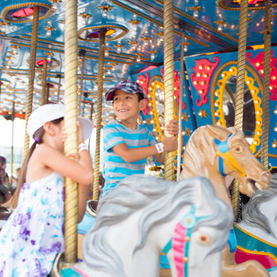 Young kids at a festival enjoying a ride on a merry-go-round horses