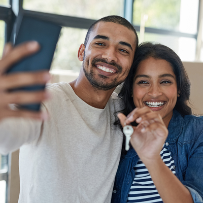 Couple smiling taking a selfie holding housekeys