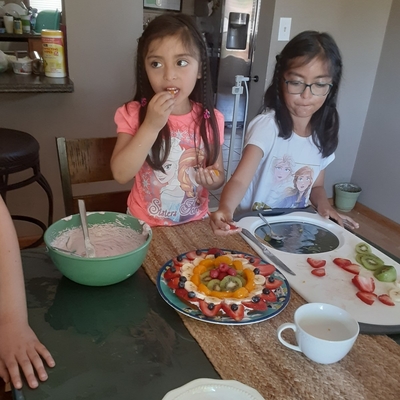 Kids eat fresh fruit pizza in a dining room