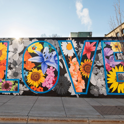 A mural of flowers with the word love in big letters on a building in Northfield, Minn by artist Brett Whitacre.