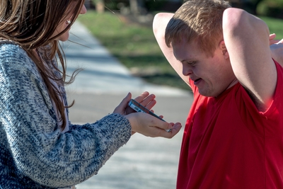 A woman showing a man with Down syndrome a phone.