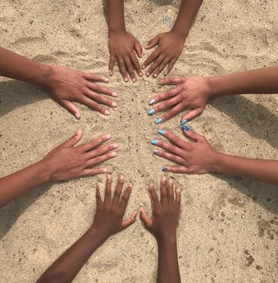 A circle of hands in the sand