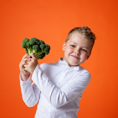 boy in white shirt holding broccoli