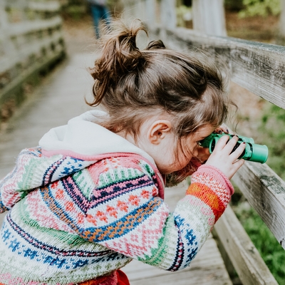 Little girl with binoculars on bridge