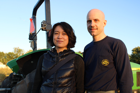 Man and woman standing in front of farm equipment