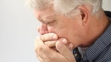 Man coughing with hands over his mouth.
