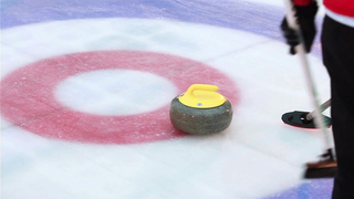 A curling stone pushed on the ice during a game between two teams.