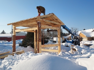Worker installing wooden pavilion in winter
