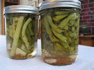 Two jars of pickled beans on a table.