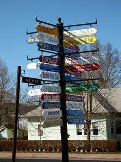 Business signs on a pole near main street