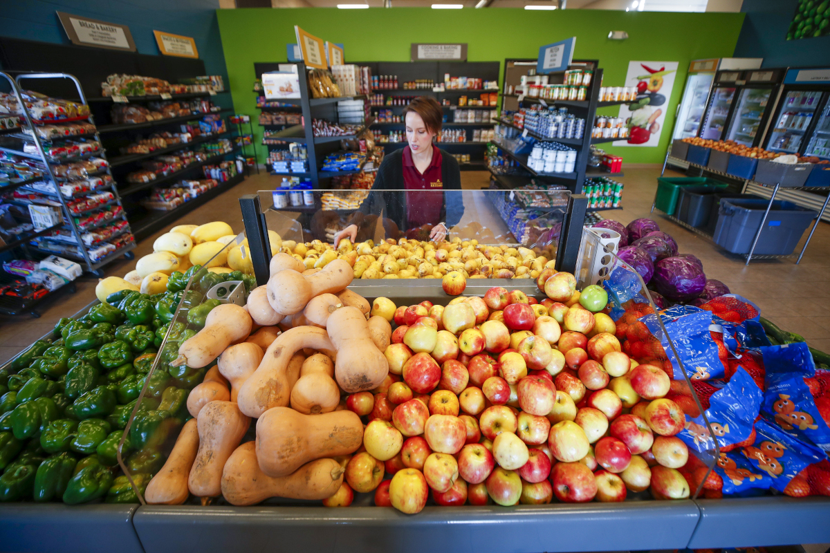 A person stocking fresh produce at a food shelf